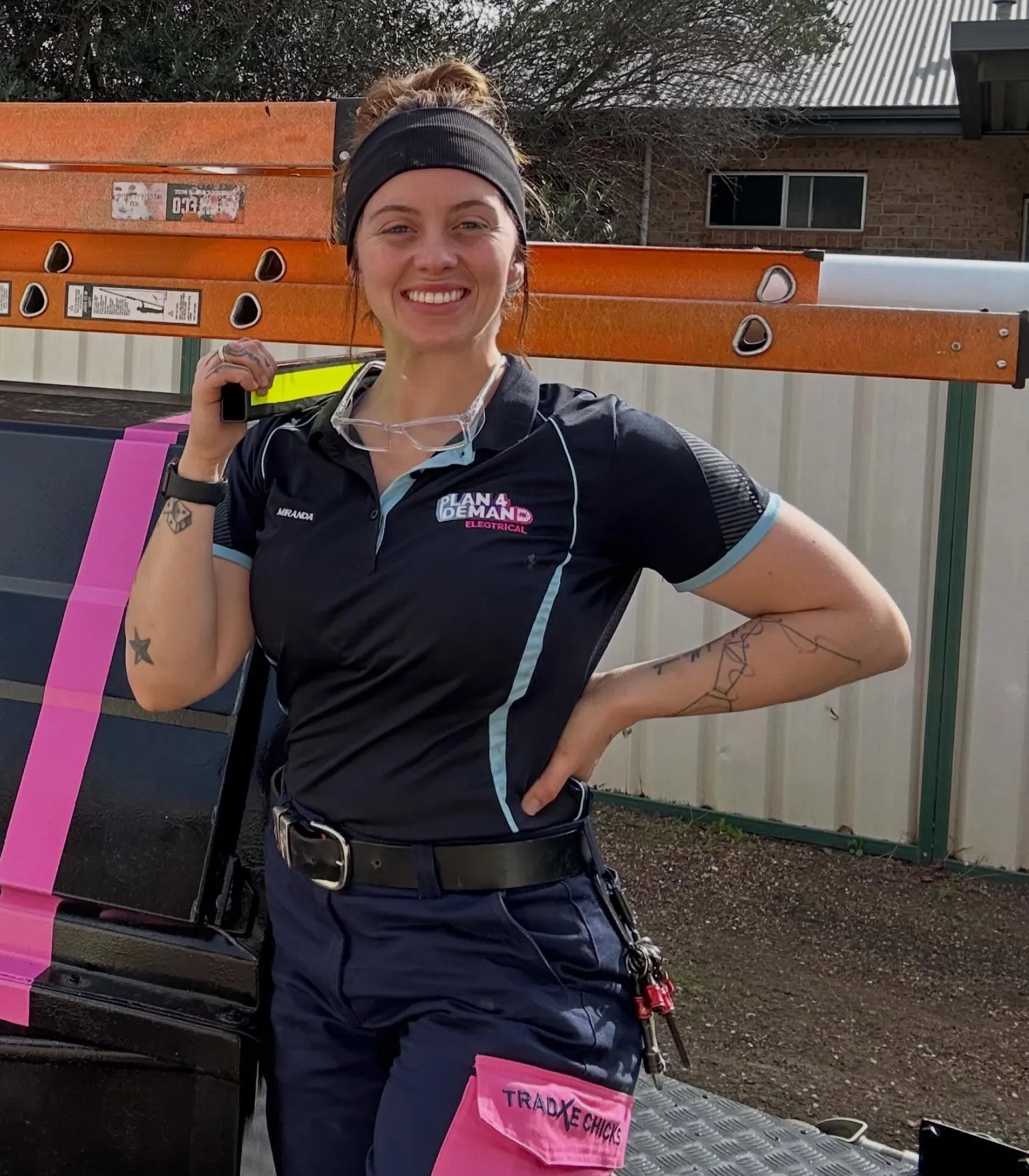 Miranda carrying a ladder on her shoulder beside her work ute