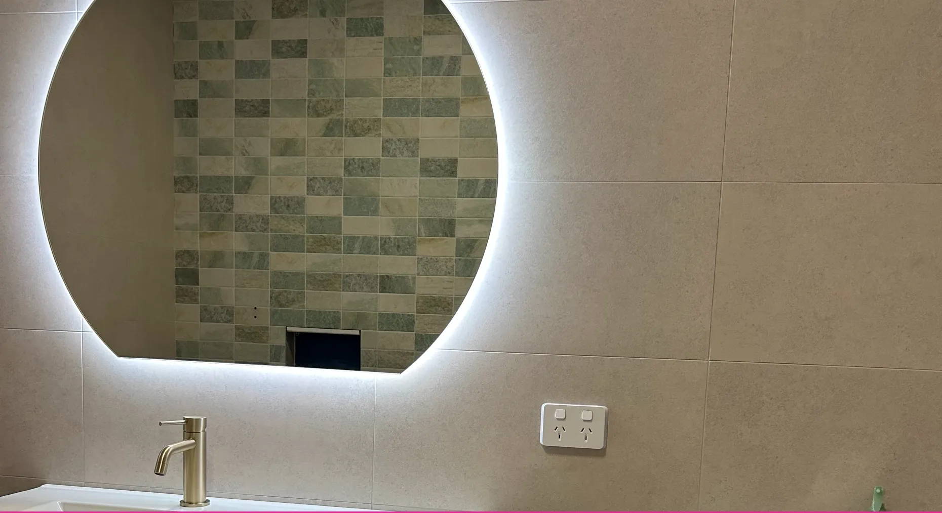 A round backlit bathroom mirror and double power point installed in a renovated bathroom